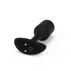 Side-angle view of black snug plug showing power button and magnetic charging ports on base