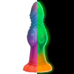 Side-by-side view of the Galactic Cock dildo in daylight pastel tones and glowing green in darkness