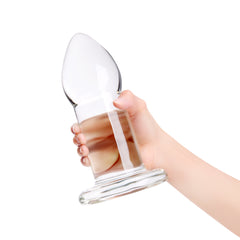Side view of hand gripping the b-Vibe glass dilator, highlighting its smooth transparent body