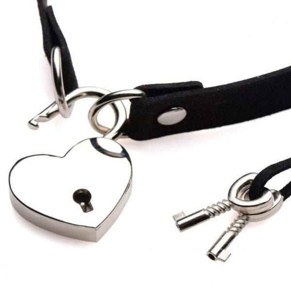 Close-up of silver heart-shaped padlock and two small skeleton keys attached to a black suede band