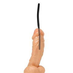 Single black silicone urethral sound trainer shown inserted into realistic model