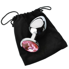 Single metal anal plug with pink gem resting beside a black velvet drawstring storage pouch