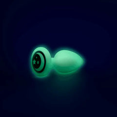 Small glow-in-the-dark silicone anal plug lying on its side showing star-detail base plate