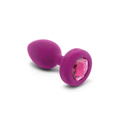 Close-up of smooth purple silicone plug laying on side, pink faceted jewel base visible