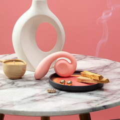 Snail GIZI dual vibrator styled on marble table with candle, incense and decorative objects, peachy pink