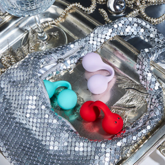 Snail TWINN vibrators in lilac, mint, and red displayed on a silver decorative tray
