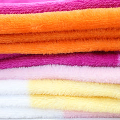 Close-up of soft plush fleece texture showing layered colorful stripes of pride blanket