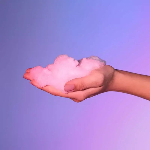 Soft white massage foam dispensed into an open palm showing light airy texture