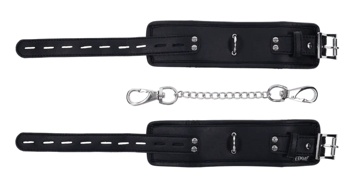 Edge padded black cuffs laid flat showing buckle straps, studs, and detachable chain