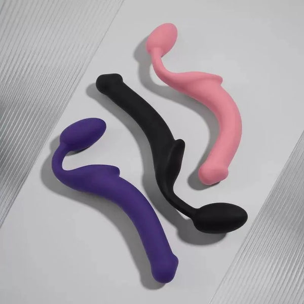 Strap-On-Me bendable strap-ons in purple, black, and pink laid flat showing curved silicone form