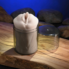Stroker nestled in clear glass storage jar with lid removed beside it