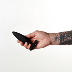 Tattooed hand holding the Je Joue Egon black silicone plug to show handheld scale