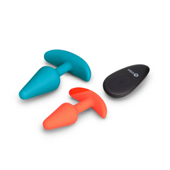 Teal and orange b-Vibe silicone anal plugs beside compact black remote, side angle
