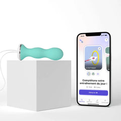 Teal Perifit kegel trainer on white cube beside smartphone showing companion app interface