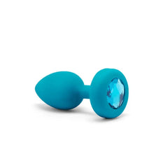 Close-up of teal silicone plug showing faceted aquamarine jewel set into flat base