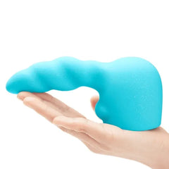 Teal silicone wand attachment with rippled texture resting in an open palm, showing soft material