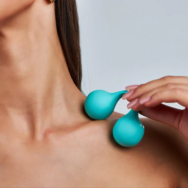 Teal TWINN vibrator held gently against a woman's shoulder illustrating soft silicone texture