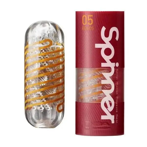 Tenga Spinner Beads 05 masturbator with gold spiral coil beside red branded tube