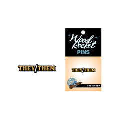 They/Them pronoun pin beside its Wood Rocket branded black and gold card backing