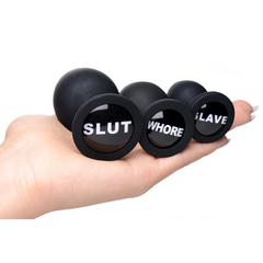 Three black silicone plugs with engraved bases shown resting on an open palm for scale