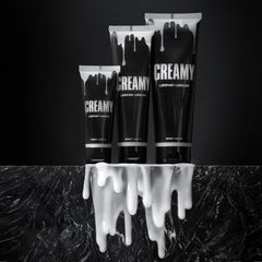 Three Creamy lubricant tubes in small medium large sizes displayed on marble surface