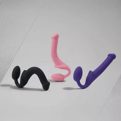 Three Strap-On-Me bendable strap-ons in black, pink, and purple showing shape flexibility