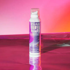 Tickle My Body massage foam bottle reflected on a glossy pink surface under warm studio lighting
