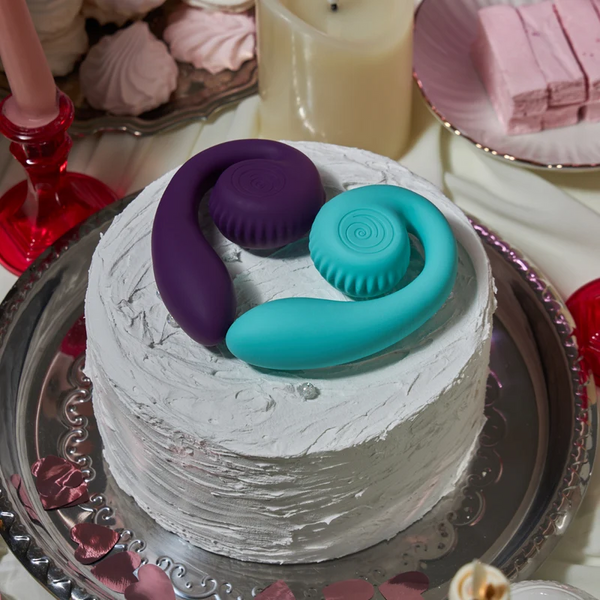 Tiffany and purple SVibe Snail GIZI vibrators displayed together atop a white frosted cake