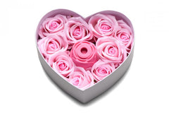 Top-down view of heart box filled with pink soap roses surrounding rose suction vibrator
