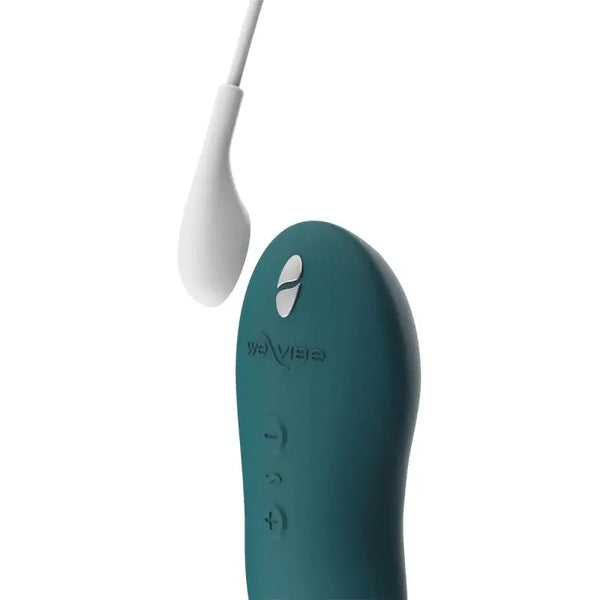 Touch X standing upright beside its magnetic USB charging cable, showing the We-Vibe logo and buttons