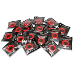 Twenty individually packaged Oxballs OXR-1 red cock rings scattered on white surface, bulk lot