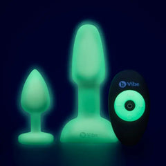 Two glow-in-the-dark silicone anal plugs and remote control glowing green in the dark