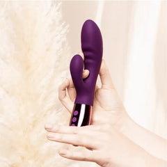 Two hands cradling Le Wand Blend dark cherry rabbit vibrator against soft backdrop
