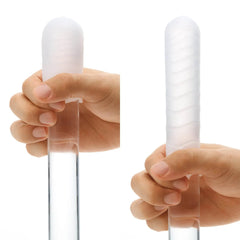 Two hands demonstrating the flexible, soft-material Pocket Tenga sleeve stretched over a clear rod