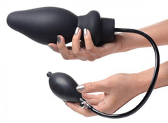 Two hands demonstrating fully inflated black silicone plug alongside squeeze-bulb hand pump