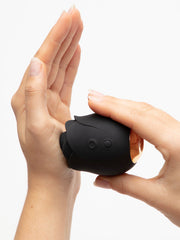 Two hands holding compact black rose silicone stimulator, demonstrating its palm-friendly size