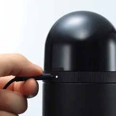 USB charging cable being inserted into the base of the black Tenga vacuum controller unit