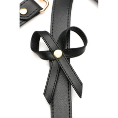 Close-up of vegan leather bow accent secured with gold rivet on black harness strap