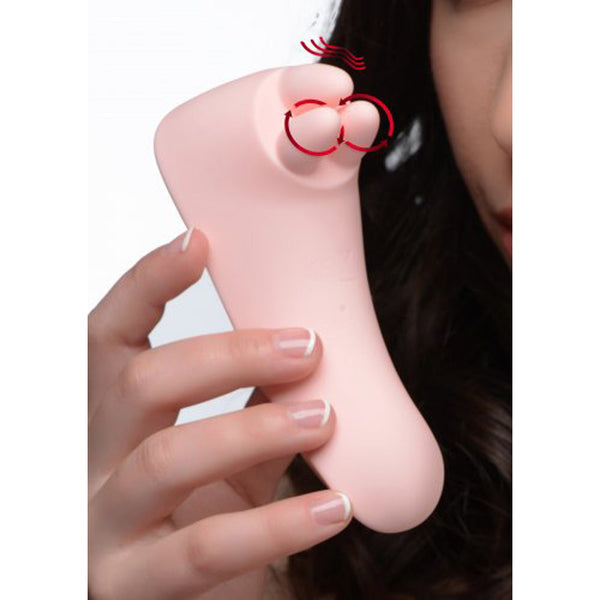 Vibrassage Fondle clit massager held in hand, showing soft pink silicone tip with motion indicators
