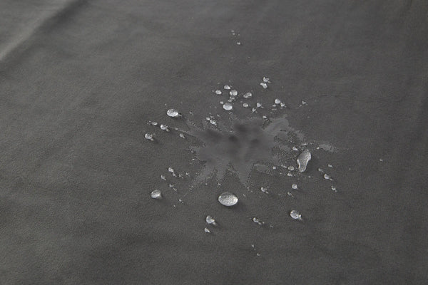 Water droplets beading on dark grey waterproof microvelvet surface of Fascinator Lush Throw King