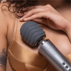 Wave-textured charcoal silicone cover on a le Wand wand massager used on upper back and shoulder