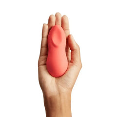 We-Vibe Touch X Crave Coral clitoral vibrator held in an open palm, showing compact size