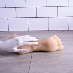 White gloved hand holding light-tone foot stroker to demonstrate realistic soft texture