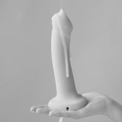 White lubricant dripping over a held silicone toy, demonstrating fluid texture