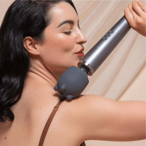Woman applying Le Wand Shiatsu deep tissue attachment to her shoulder and upper back area for muscle relief