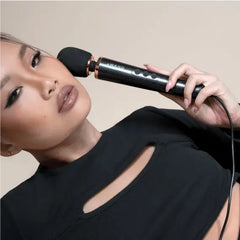 Woman holding Le Wand Petite massager head near jaw showing personal massage use