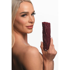Woman holding unlit red Thorn Drip Candle beside her face showing size and surface detail
