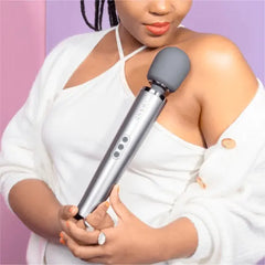 Woman in white top holding Le Wand massager against her shoulder demonstrating comfortable full-hand grip